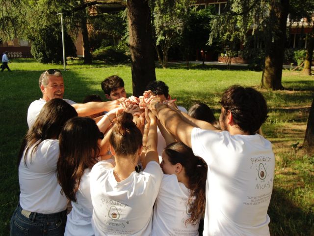 Volontari di Project Nicky con le mani unite al centro di un cerchio, in un parco