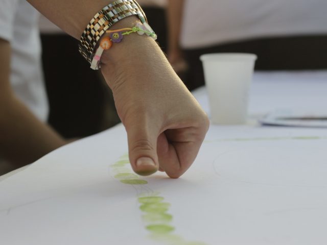 Mano che imprime un’impronta di colore verde su un cartellone